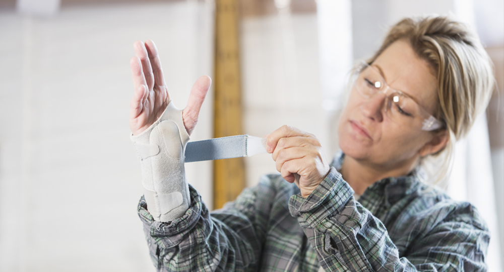 Female warehouse employee wrapping splint around her wrist